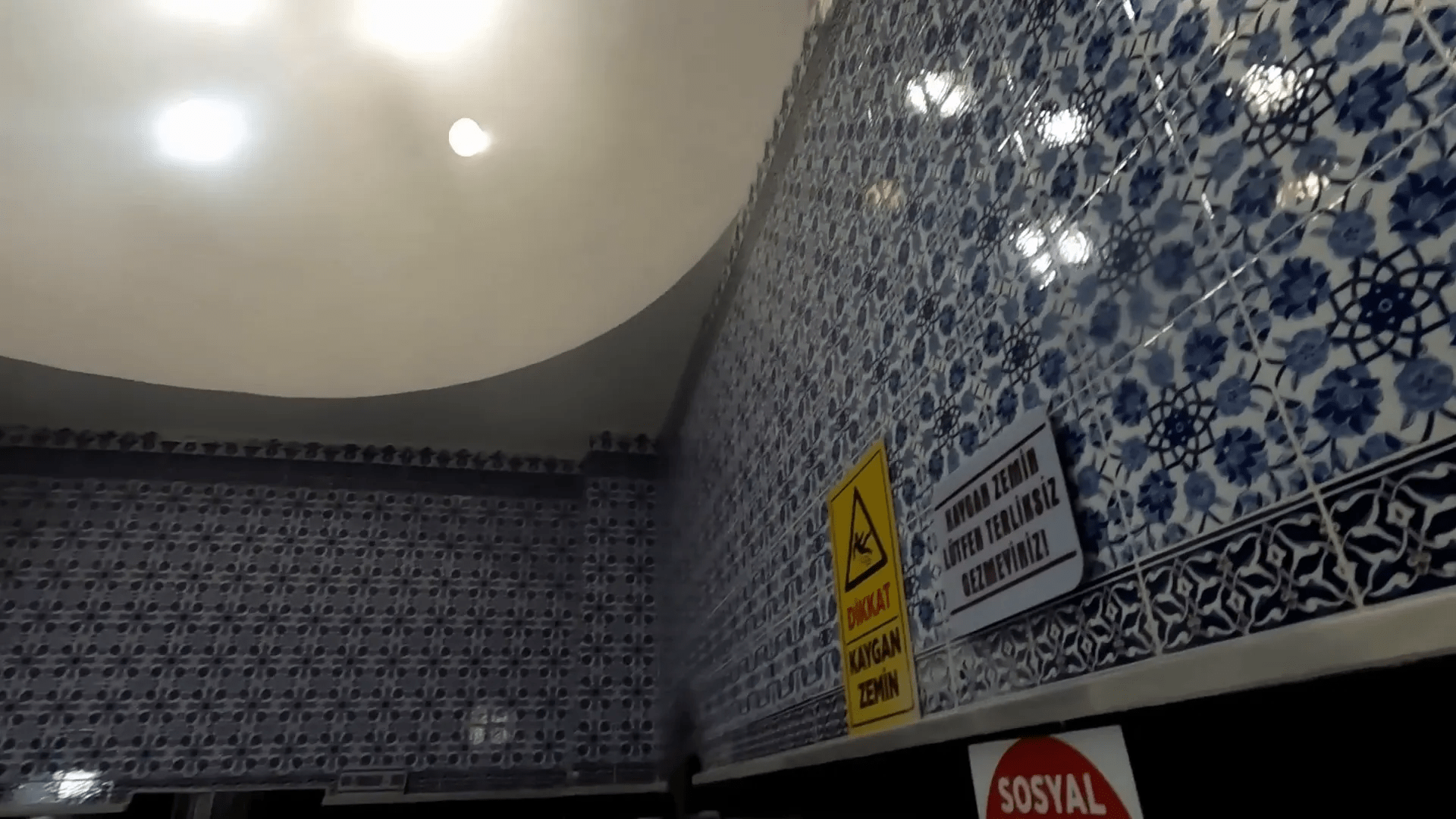 Hamamın içi, mavi fayanslarla kaplı ve sıcak bir ortam.